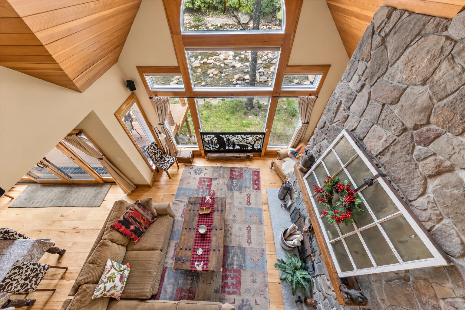 Sunroom addition with tall wood-framed windows, a stone fireplace, and a cozy seating area beneath a vaulted wood ceiling.